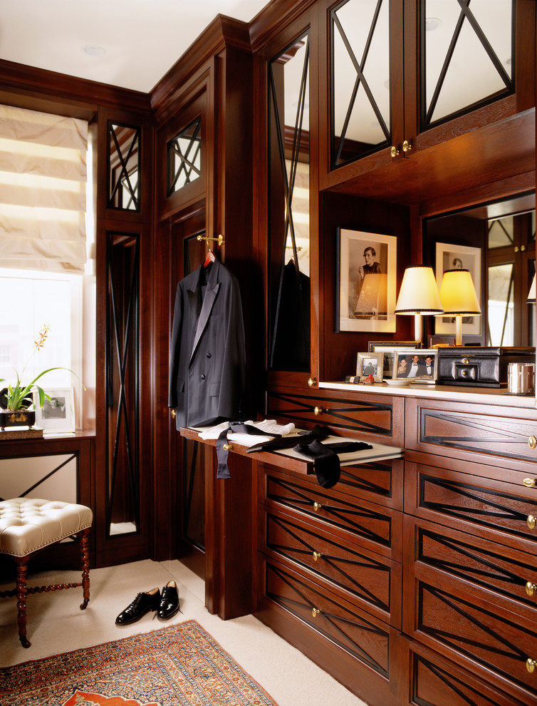 Elegant men's walk-in closet photo in Chicago with dark wood cabinets
