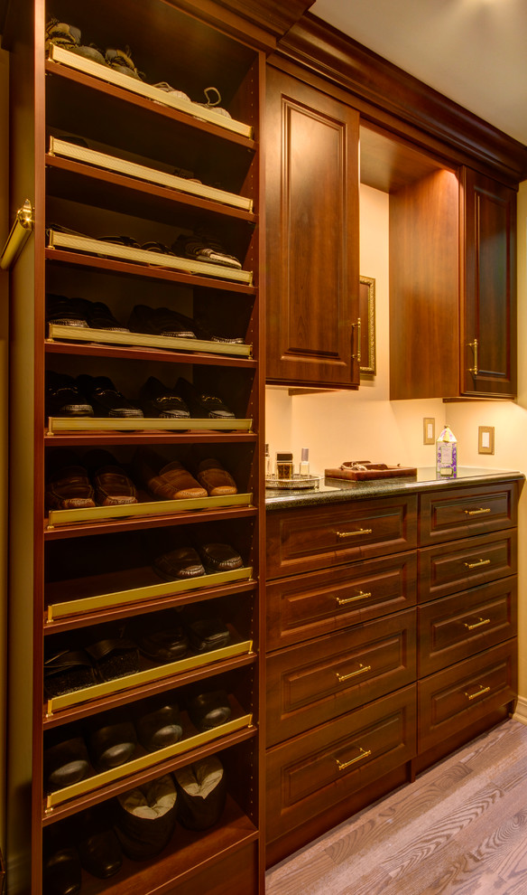 Walk-in closet - mid-sized traditional men's medium tone wood floor and brown floor walk-in closet idea in Other with raised-panel cabinets and dark wood cabinets