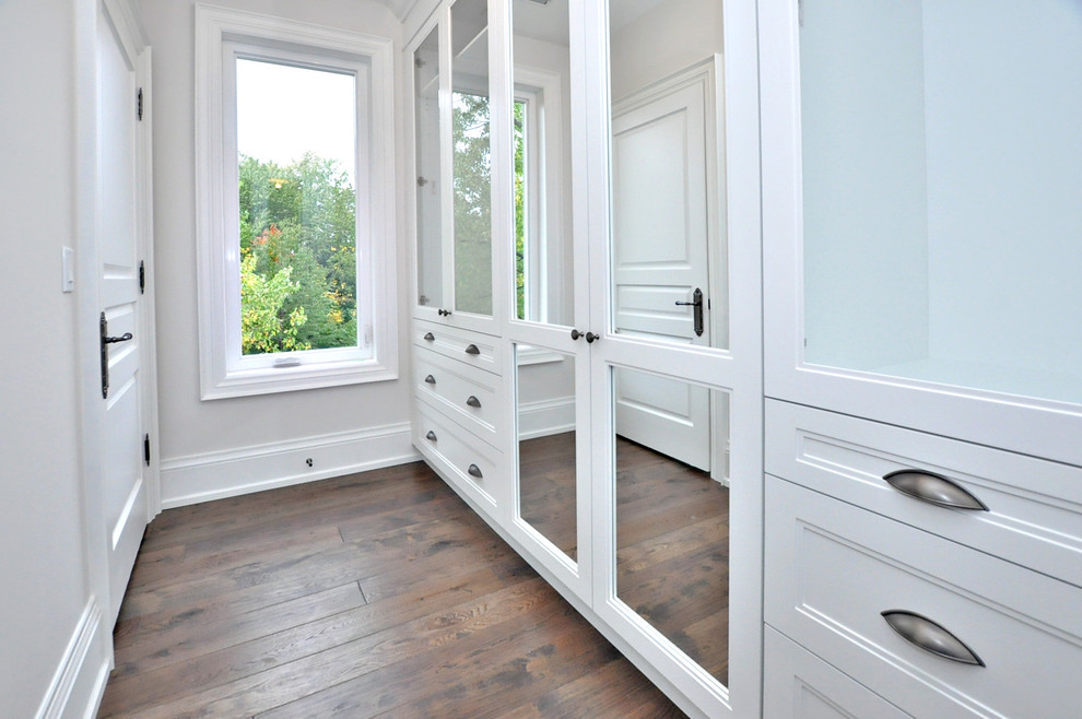 Foto de armario unisex tradicional renovado con armarios con paneles empotrados, puertas de armario blancas y suelo de madera en tonos medios