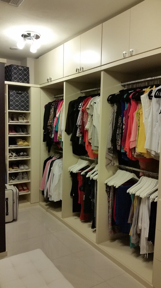 Ejemplo de armario vestidor de mujer moderno grande con armarios con paneles lisos, suelo de baldosas de porcelana, suelo beige y puertas de armario beige