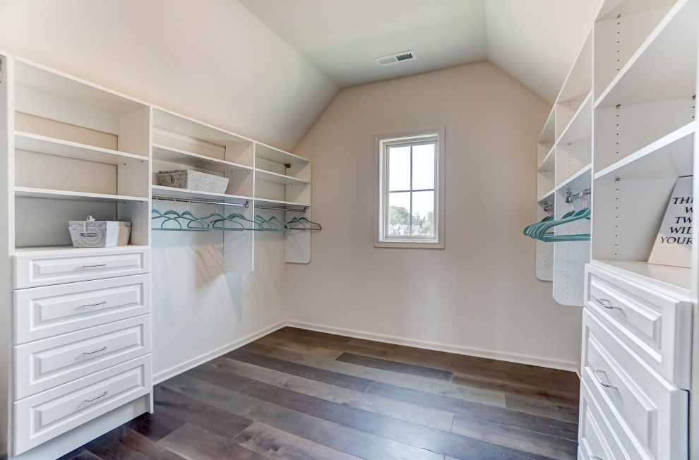 Inspiration for an expansive walk-in wardrobe for women in Charlotte with raised-panel cabinets, white cabinets, dark hardwood flooring and a vaulted ceiling.