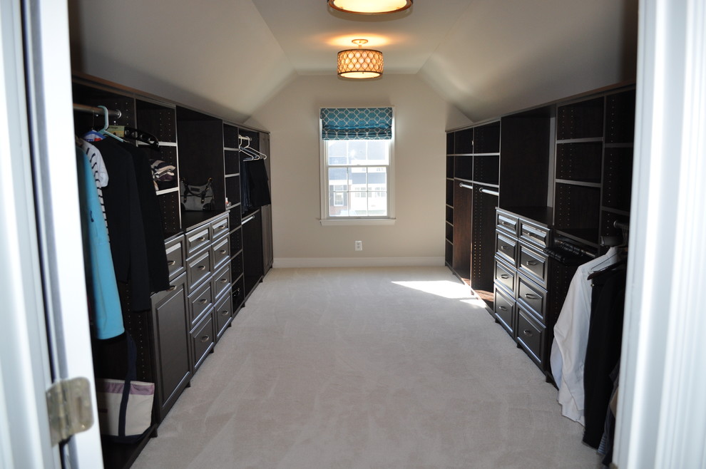 Imagen de vestidor unisex clásico grande con armarios con paneles con relieve, puertas de armario de madera en tonos medios y moqueta