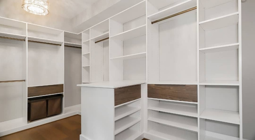 Diseño de vestidor unisex minimalista grande con armarios con paneles lisos, puertas de armario blancas, suelo de madera oscura y suelo marrón