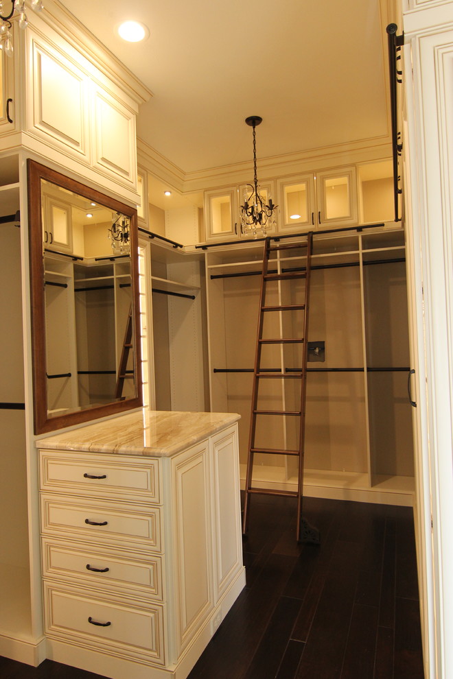 Inredning av ett klassiskt stort walk-in-closet, med luckor med upphöjd panel, beige skåp, mörkt trägolv och brunt golv