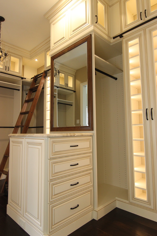 Inspiration för stora klassiska walk-in-closets, med luckor med upphöjd panel, beige skåp, mörkt trägolv och brunt golv