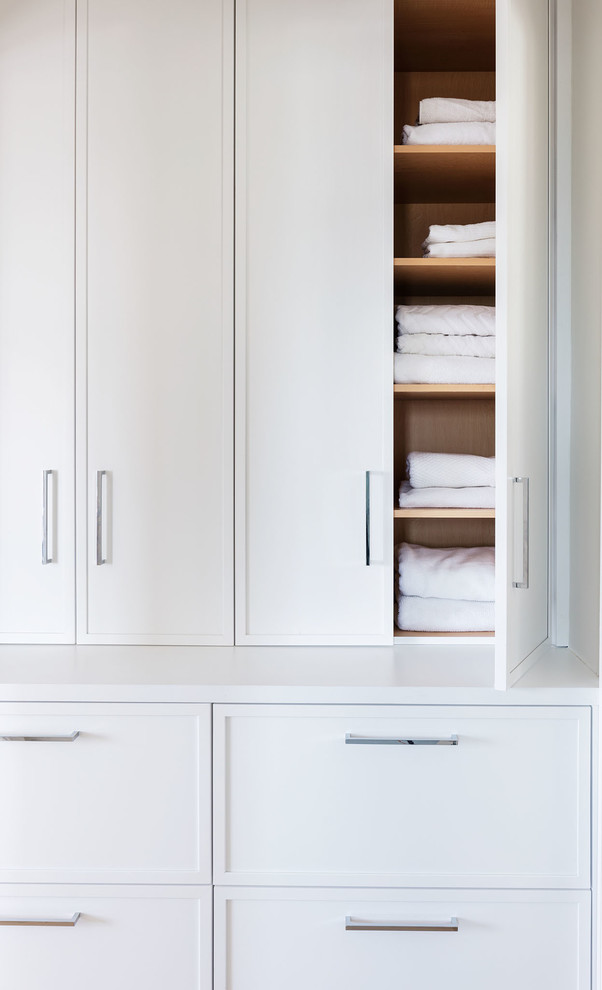 Ejemplo de armario clásico renovado pequeño con puertas de armario blancas, suelo de madera clara y suelo marrón