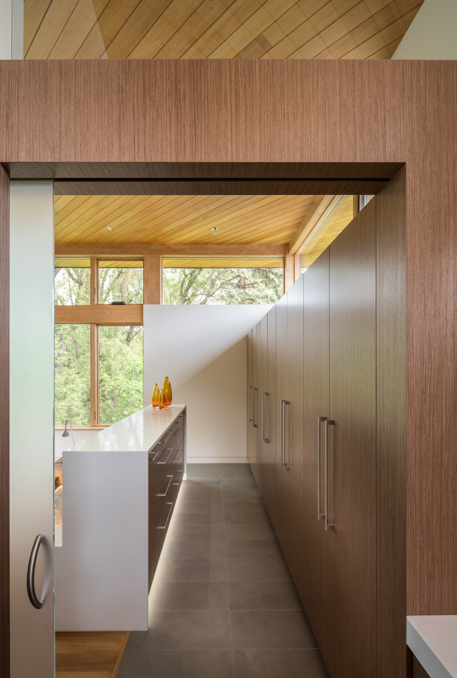 Idées déco pour un dressing room contemporain en bois foncé neutre avec un placard à porte plane, un sol en carrelage de porcelaine et un sol gris.