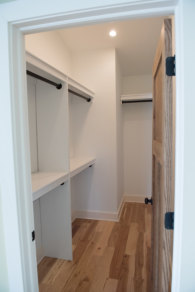 Example of a mid-sized arts and crafts gender-neutral light wood floor and beige floor walk-in closet design in Indianapolis with open cabinets and white cabinets