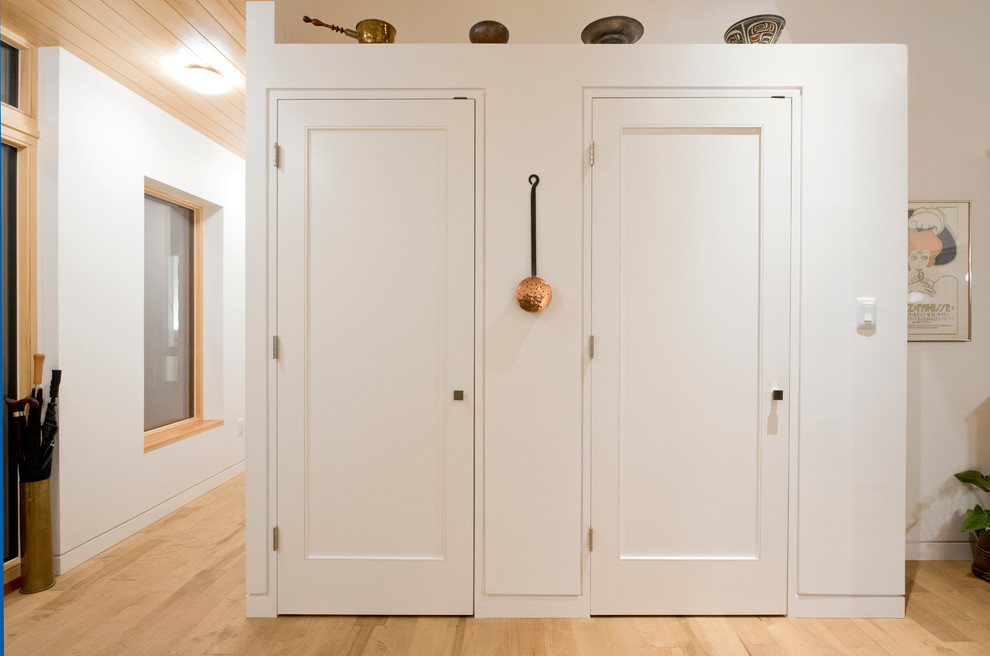 Imagen de armario unisex contemporáneo pequeño con suelo de madera clara