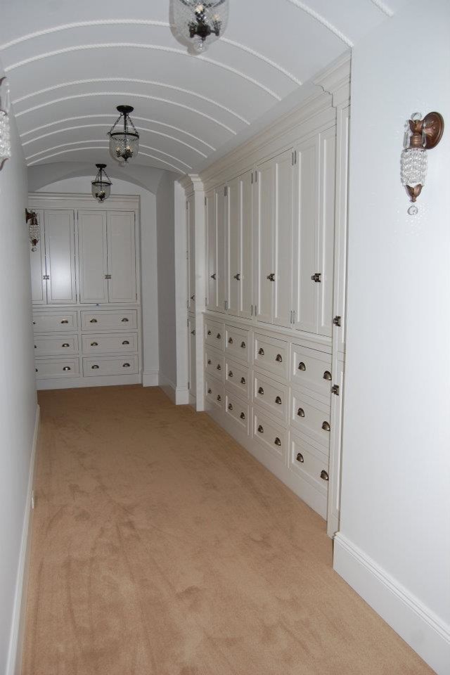 Пример оригинального дизайна: большая гардеробная комната унисекс с фасадами с утопленной филенкой, белыми фасадами и паркетным полом среднего тона