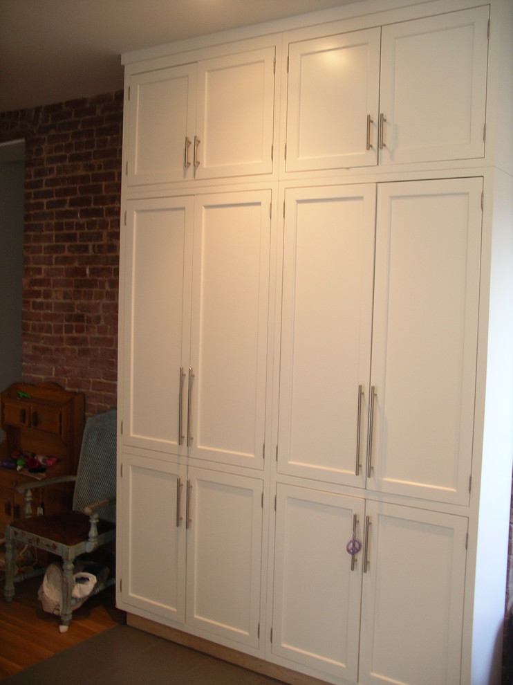 Imagen de armario unisex minimalista de tamaño medio con armarios con paneles empotrados, puertas de armario blancas y suelo de madera en tonos medios
