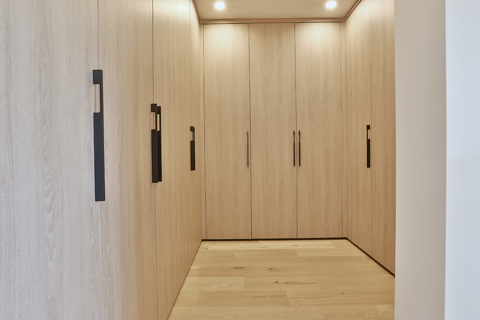 Idéer för ett mellanstort modernt walk-in-closet för könsneutrala, med släta luckor, skåp i ljust trä, ljust trägolv och beiget golv