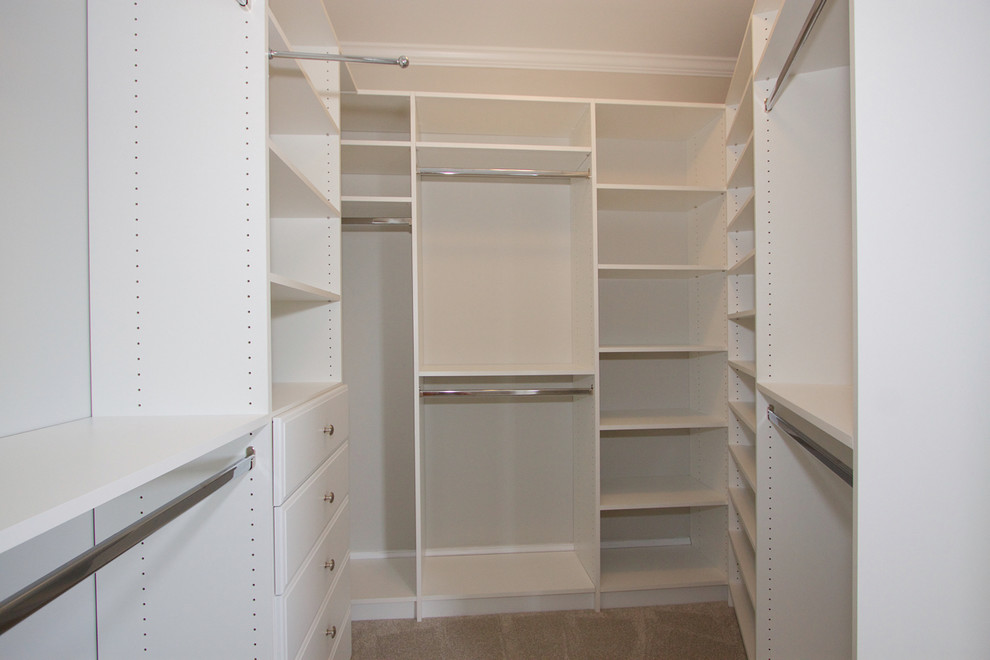 Imagen de armario vestidor unisex tradicional de tamaño medio con armarios abiertos, puertas de armario blancas y moqueta