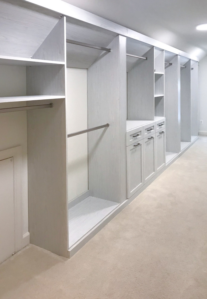 Inspiration for a large traditional gender neutral walk-in wardrobe with recessed-panel cabinets, light wood cabinets, carpet and beige floors.