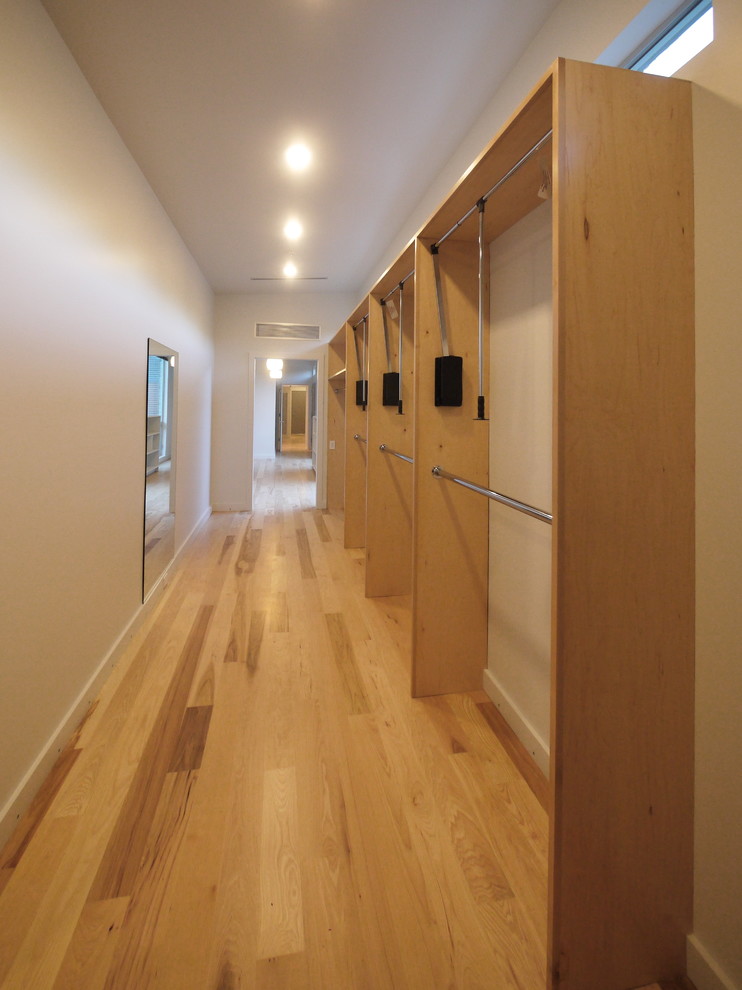Idée de décoration pour un grand dressing room minimaliste en bois clair pour une femme avec un placard à porte plane et un sol en bois brun.