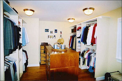 Modelo de armario vestidor unisex clásico grande con puertas de armario de madera oscura, suelo de madera en tonos medios y armarios con paneles lisos