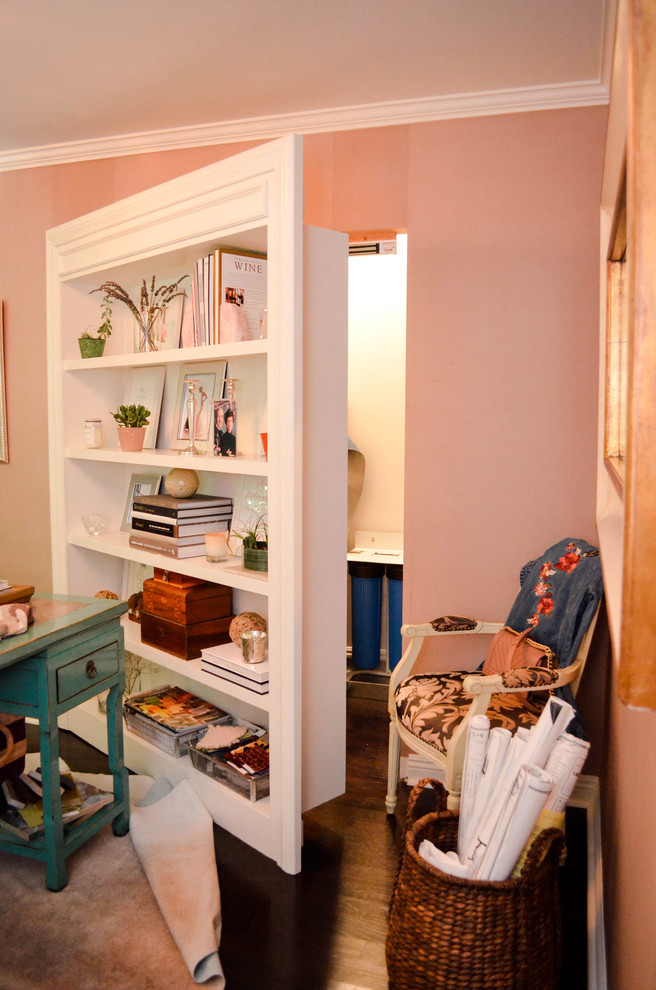 Inredning av ett litet walk-in-closet för könsneutrala, med vita skåp, mörkt trägolv och brunt golv