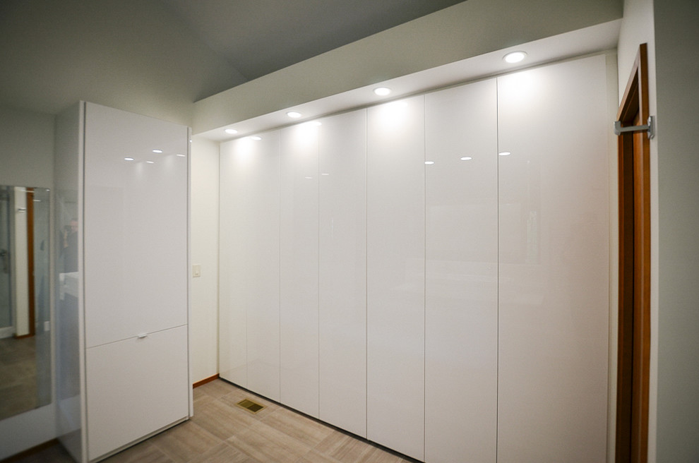 Cette image montre un grand dressing room design avec un placard à porte plane, des portes de placard blanches et moquette.