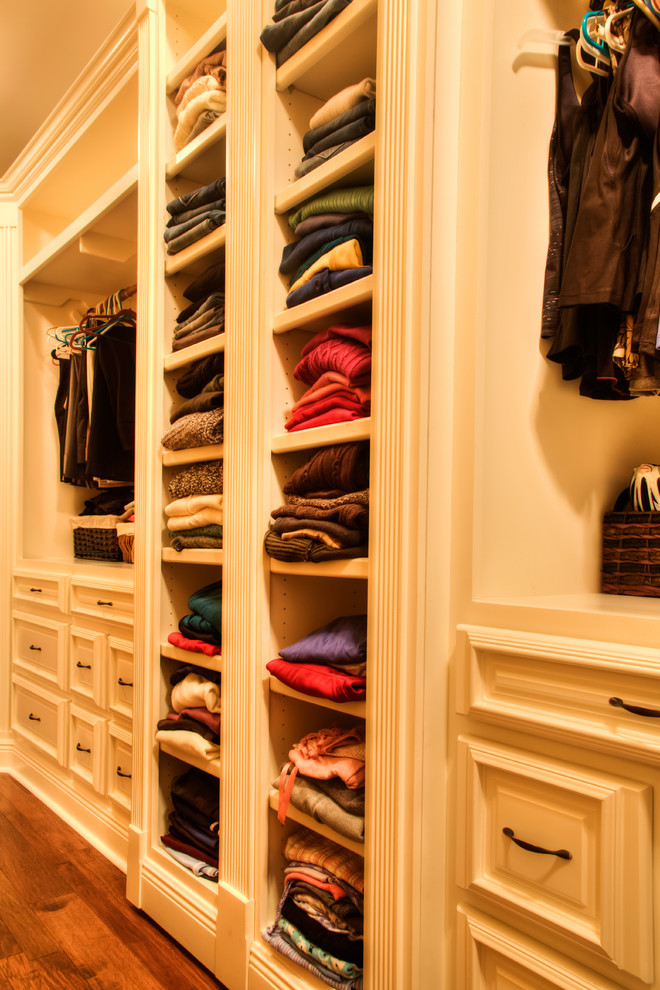 Foto de armario vestidor unisex de estilo americano con armarios con paneles con relieve, puertas de armario blancas y suelo de madera en tonos medios