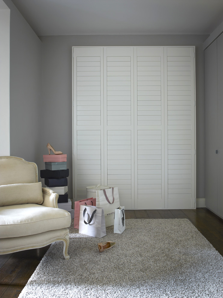 Foto de vestidor unisex tradicional renovado con puertas de armario blancas y suelo de madera oscura