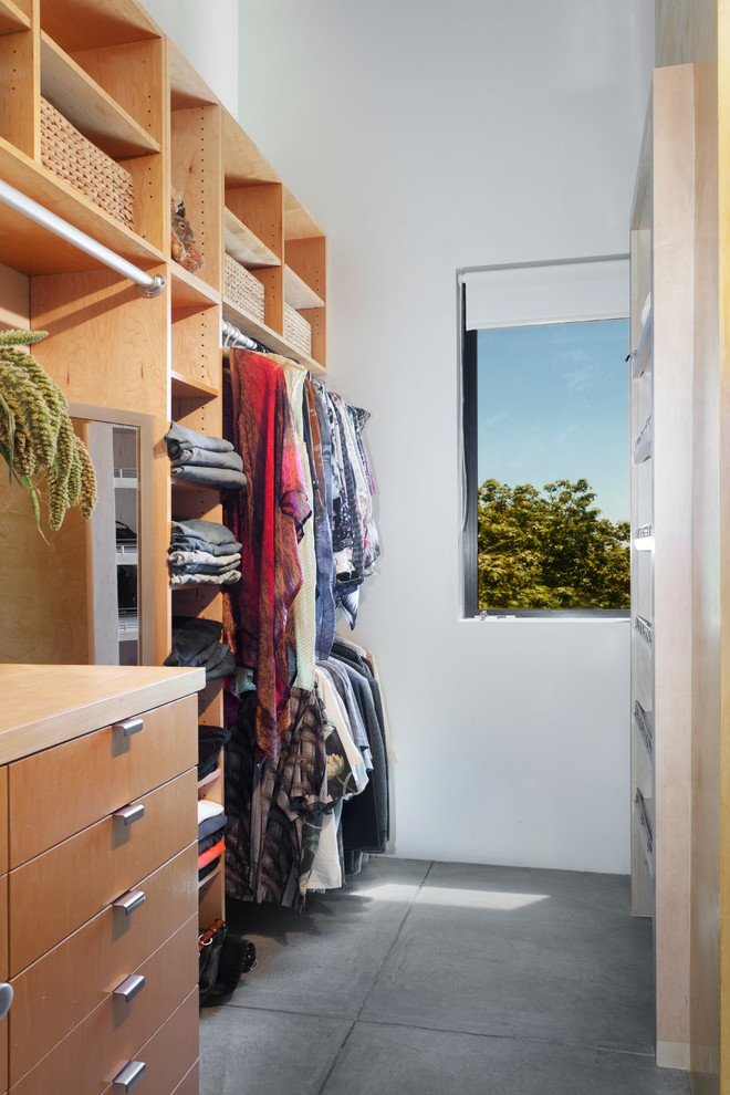 Modelo de armario vestidor unisex actual de tamaño medio con puertas de armario de madera clara y suelo de cemento