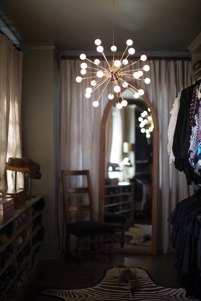 На фото: гардеробная комната среднего размера, унисекс в стиле ретро с темными деревянными фасадами и коричневым полом с