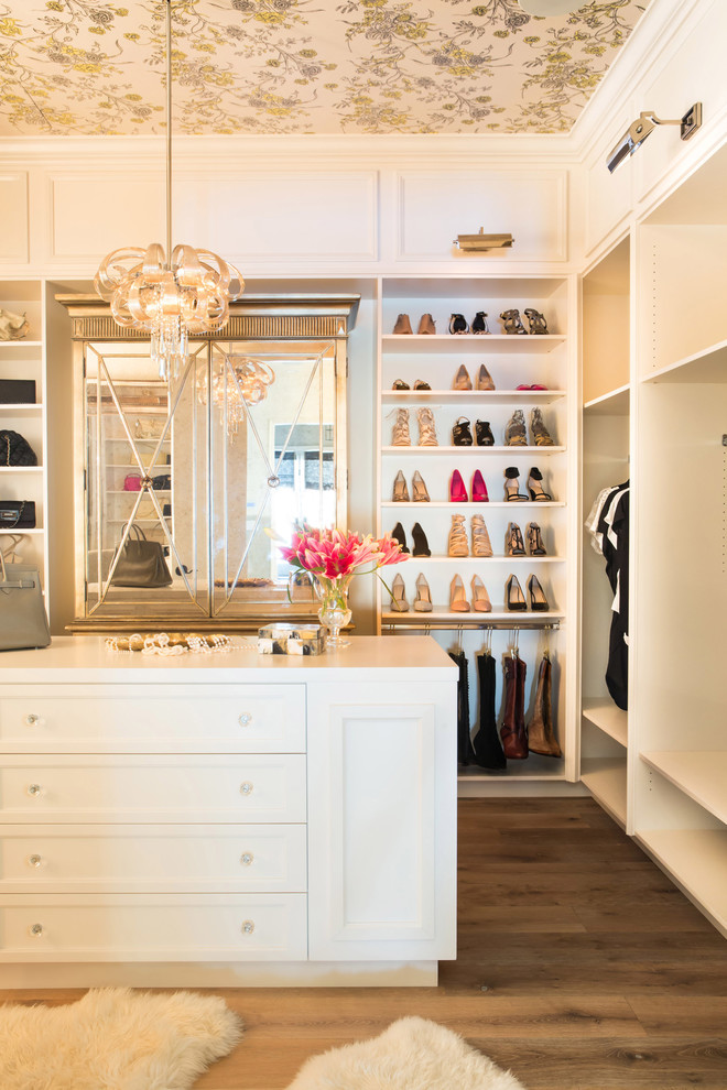 Aménagement d'un dressing et rangement classique pour une femme avec des portes de placard blanches et un sol marron.