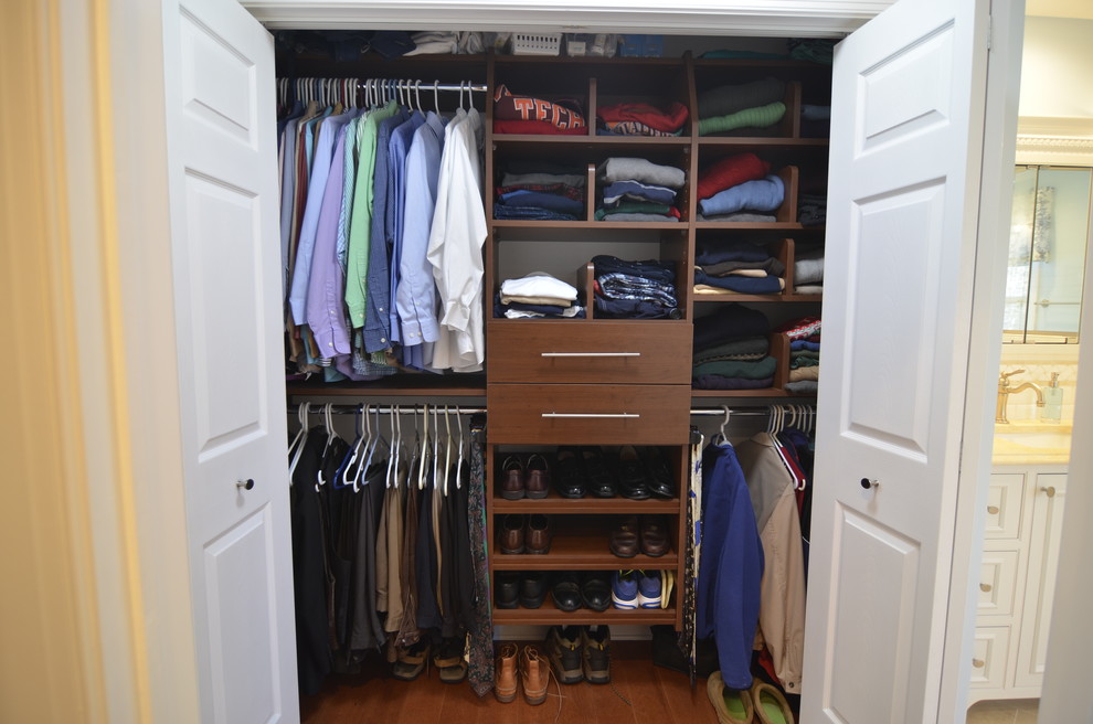 Diseño de armario de hombre minimalista de tamaño medio con armarios con paneles lisos, puertas de armario marrones y suelo de madera en tonos medios