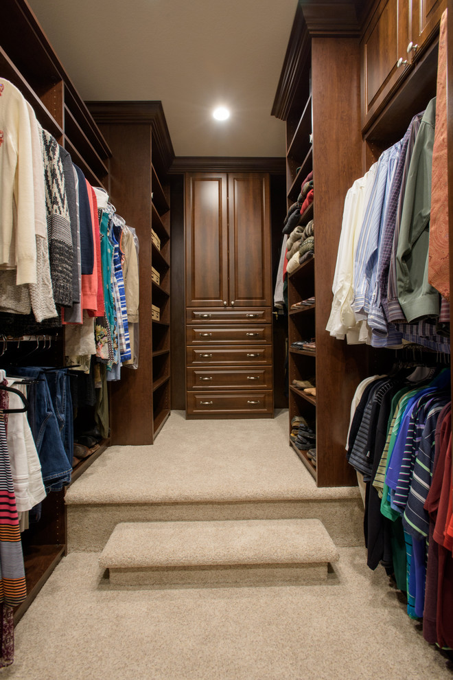 Inspiration for a medium sized traditional gender neutral walk-in wardrobe in Denver with raised-panel cabinets, medium wood cabinets, carpet and beige floors.