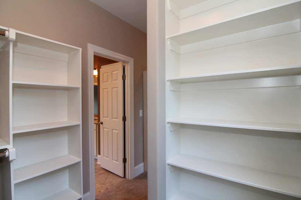 This is an example of a large classic gender neutral walk-in wardrobe in Raleigh with carpet.