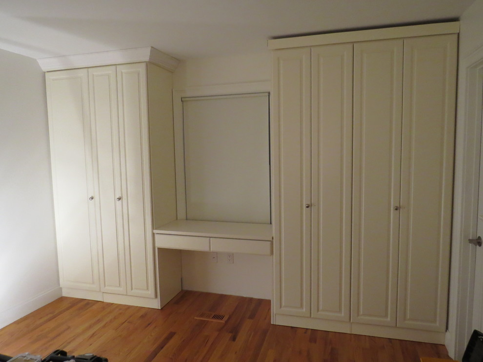 Foto de vestidor unisex campestre de tamaño medio con armarios con paneles con relieve, puertas de armario blancas y suelo de madera oscura
