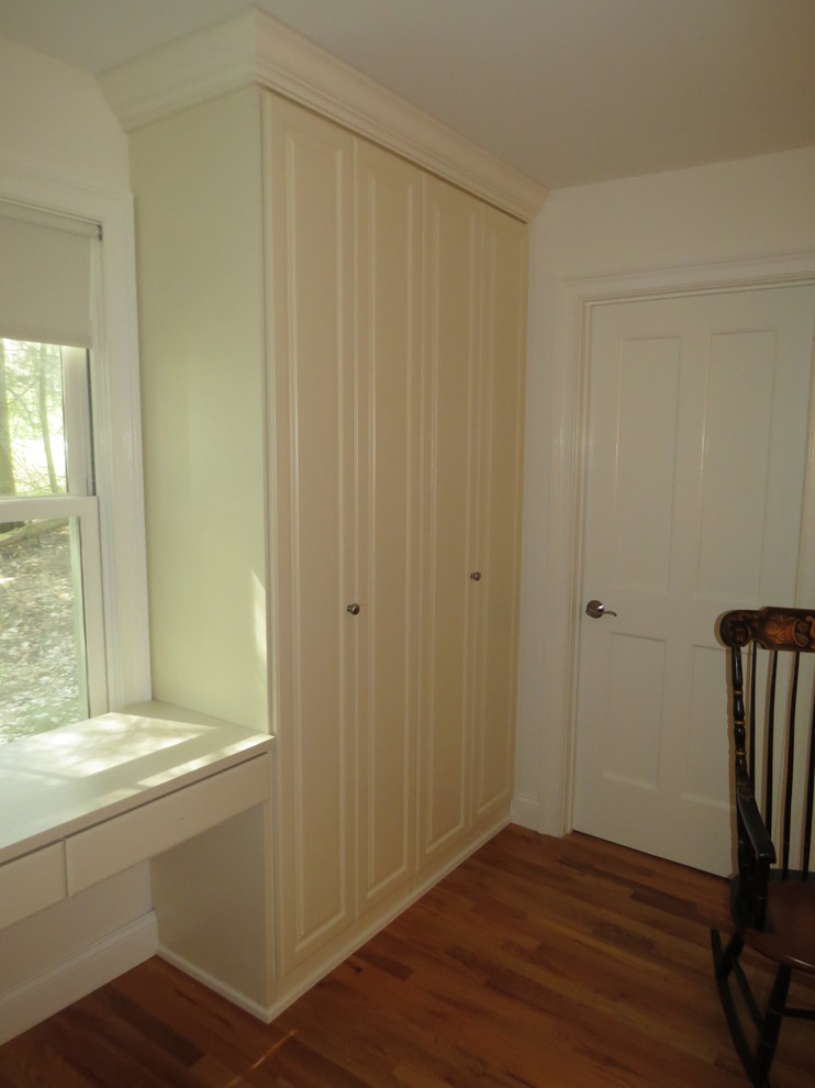 Idée de décoration pour un dressing room champêtre de taille moyenne et neutre avec un placard avec porte à panneau surélevé, des portes de placard blanches et parquet foncé.