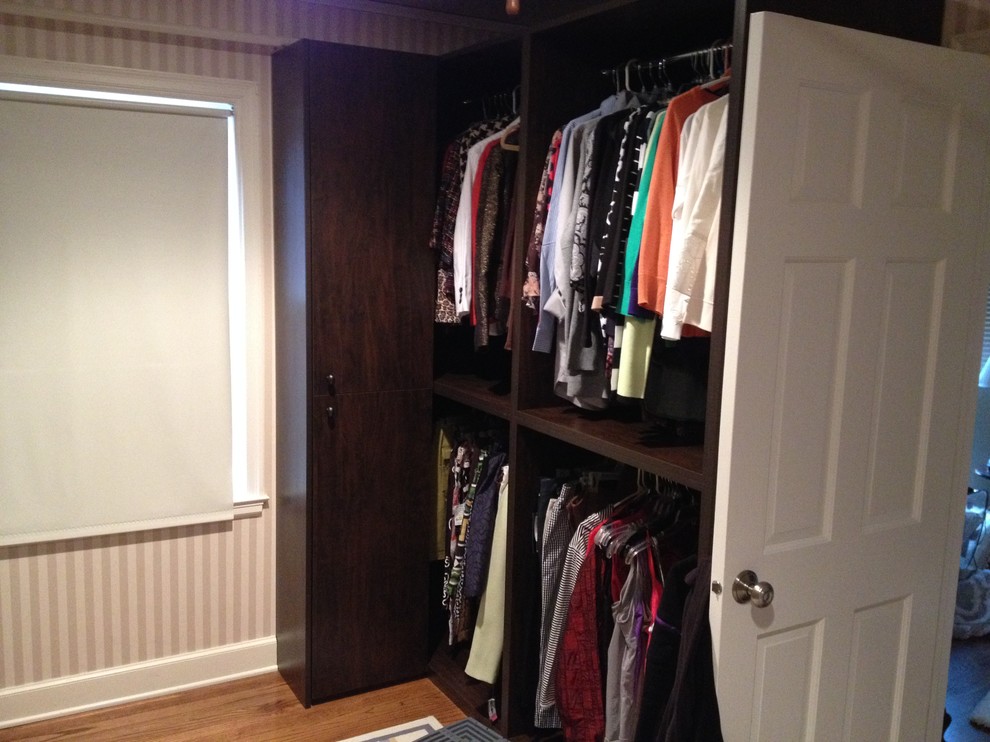 Design ideas for a medium sized contemporary gender neutral walk-in wardrobe in Omaha with flat-panel cabinets, dark wood cabinets, medium hardwood flooring and brown floors.