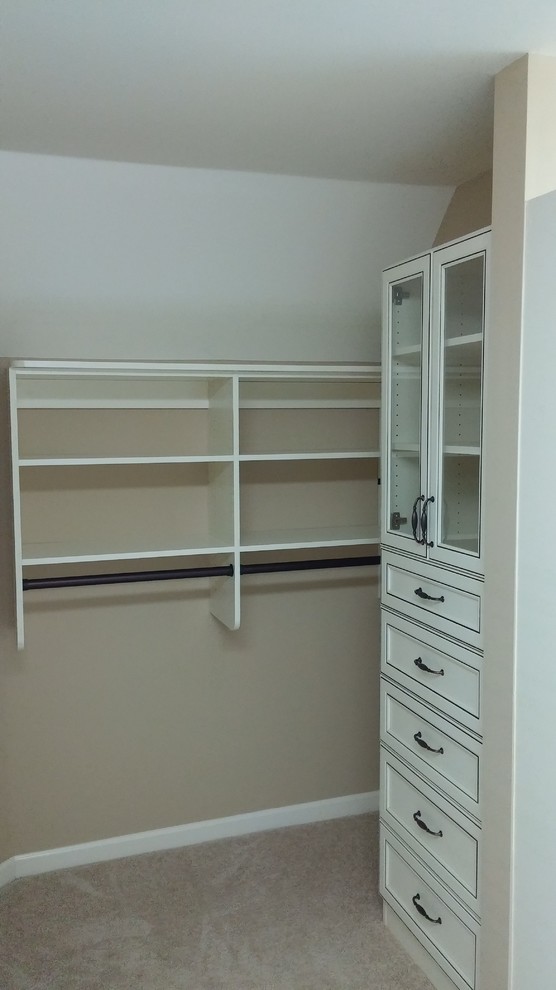 This is an example of a medium sized classic gender neutral walk-in wardrobe in Atlanta with glass-front cabinets, distressed cabinets, carpet and beige floors.