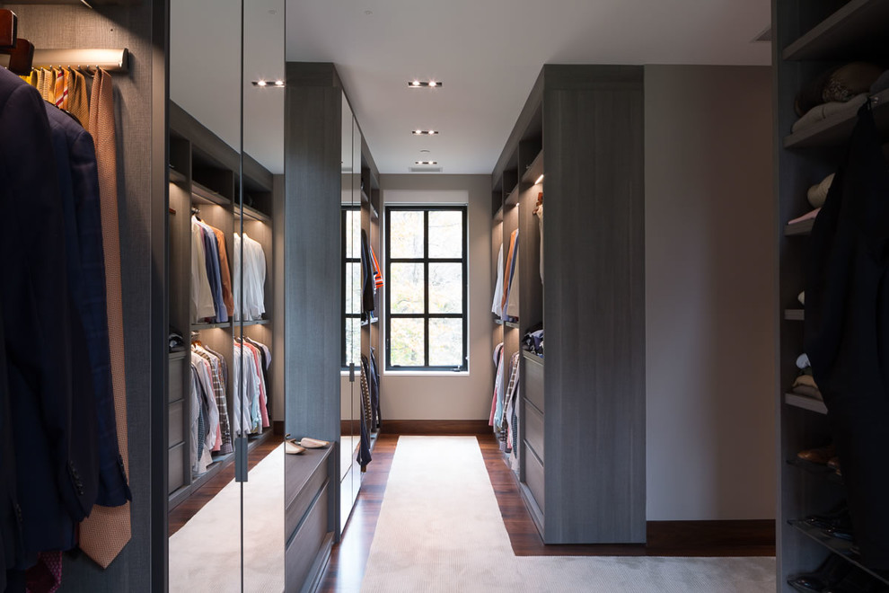 Ejemplo de armario vestidor de hombre actual extra grande con armarios con paneles lisos, puertas de armario de madera oscura, moqueta y suelo beige