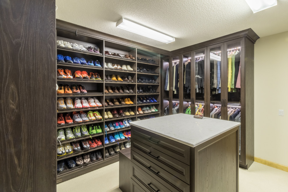 Example of a large trendy men's carpeted walk-in closet design in Minneapolis with recessed-panel cabinets and dark wood cabinets