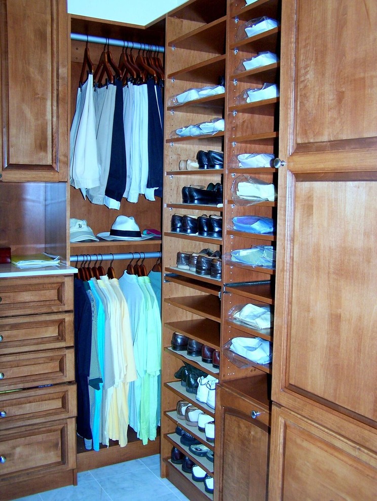 Ejemplo de armario vestidor de hombre clásico pequeño con armarios con paneles con relieve, puertas de armario de madera oscura y suelo de baldosas de cerámica