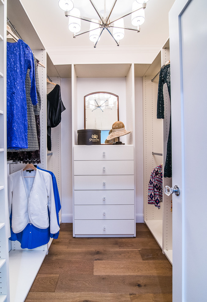 Idéer för mellanstora vintage walk-in-closets för könsneutrala, med släta luckor, vita skåp, mellanmörkt trägolv och brunt golv