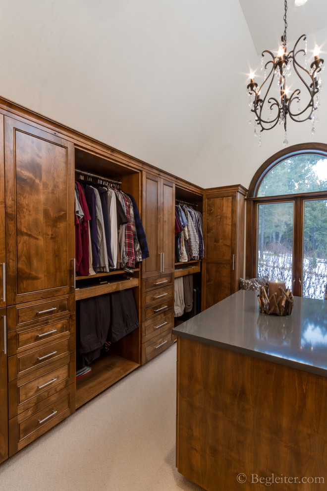 Imagen de armario vestidor unisex tradicional renovado grande con armarios con paneles con relieve, puertas de armario de madera oscura y moqueta