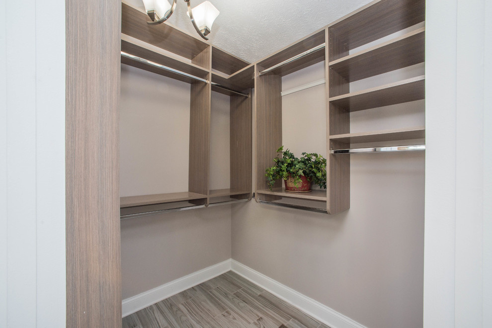 Imagen de armario vestidor unisex tradicional de tamaño medio con armarios abiertos, puertas de armario de madera oscura, suelo de baldosas de porcelana y suelo gris