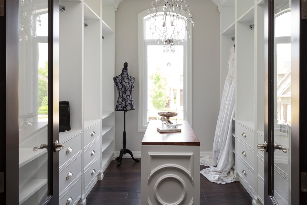 Inspiration for a timeless women's dark wood floor walk-in closet remodel in Toronto with white cabinets and flat-panel cabinets