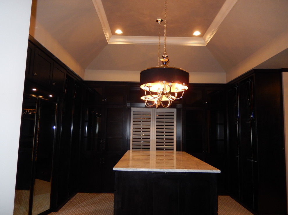 Idée de décoration pour un grand dressing room tradition neutre avec des portes de placard noires et moquette.