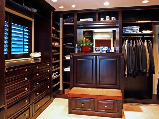 Modelo de armario vestidor de hombre clásico de tamaño medio con armarios con paneles con relieve, puertas de armario de madera en tonos medios y moqueta