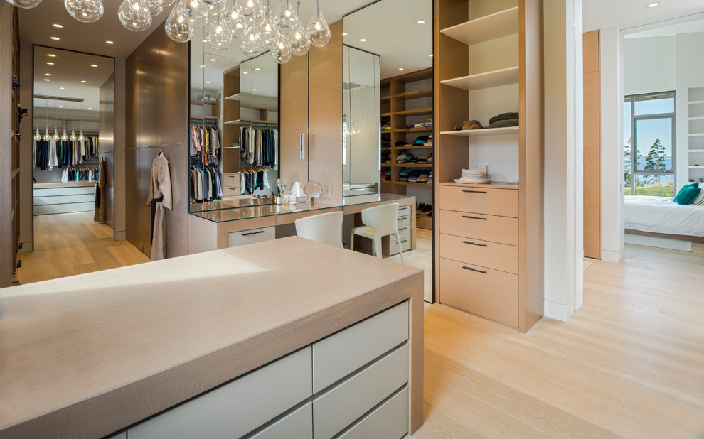 Inspiration for a contemporary gender neutral dressing room in Toronto with flat-panel cabinets, light wood cabinets, light hardwood flooring, beige floors and feature lighting.