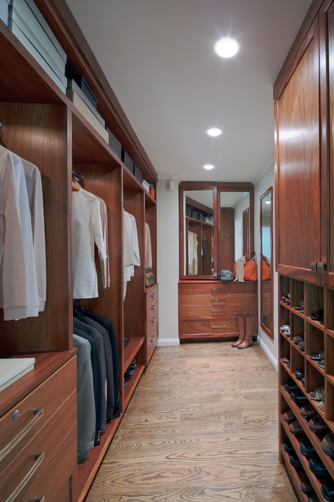 This is an example of a medium sized traditional gender neutral dressing room in New York with recessed-panel cabinets, medium wood cabinets and medium hardwood flooring.