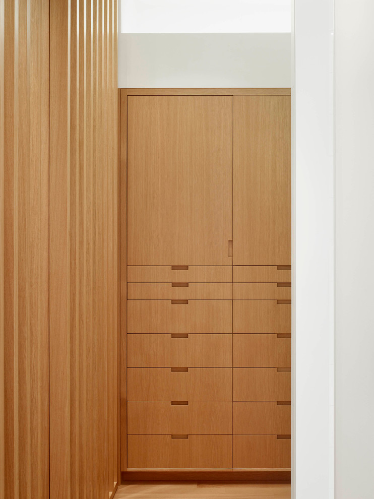 Inspiration for a small modern gender neutral walk-in wardrobe in Toronto with flat-panel cabinets, light wood cabinets, light hardwood flooring and beige floors.
