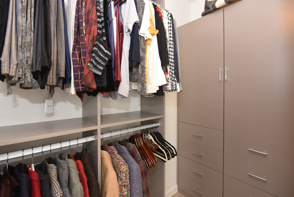 Imagen de armario vestidor unisex vintage con armarios con paneles lisos, puertas de armario beige, suelo de baldosas de porcelana y suelo beige