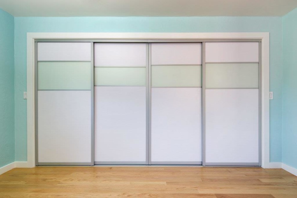 Foto de armario unisex actual con armarios con paneles lisos, puertas de armario blancas y suelo de madera en tonos medios