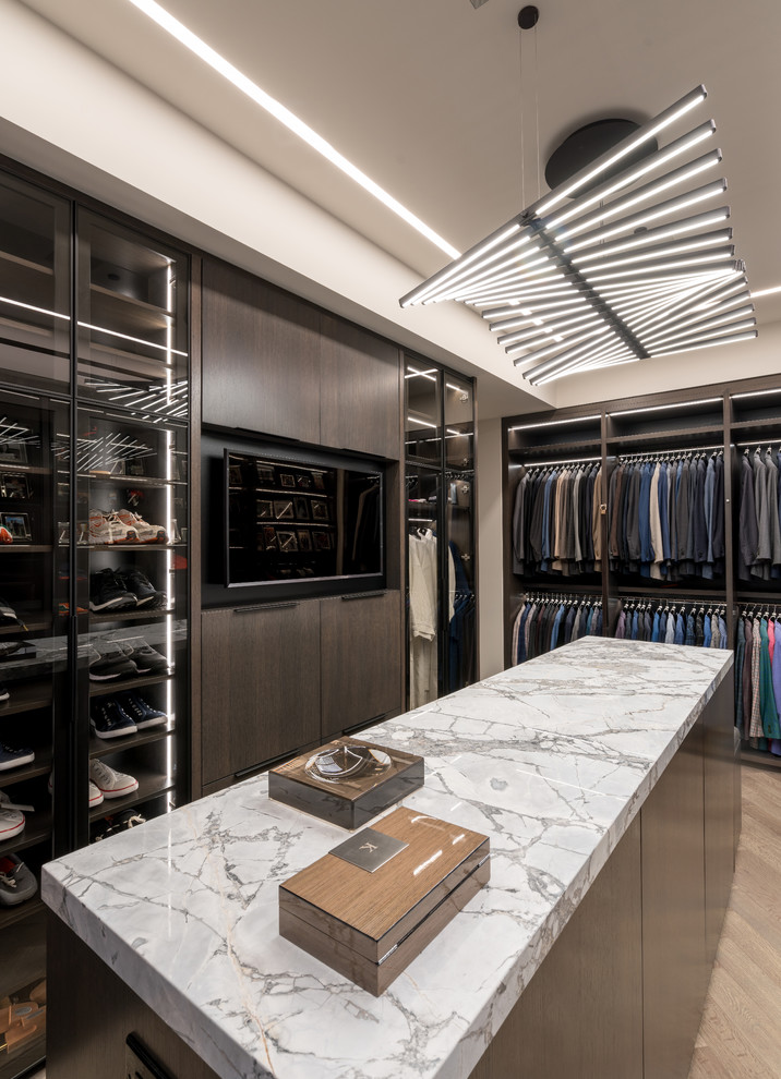 Contemporary gender-neutral walk-in wardrobe in Miami with flat-panel cabinets, dark wood cabinets, light hardwood floors and beige floor.