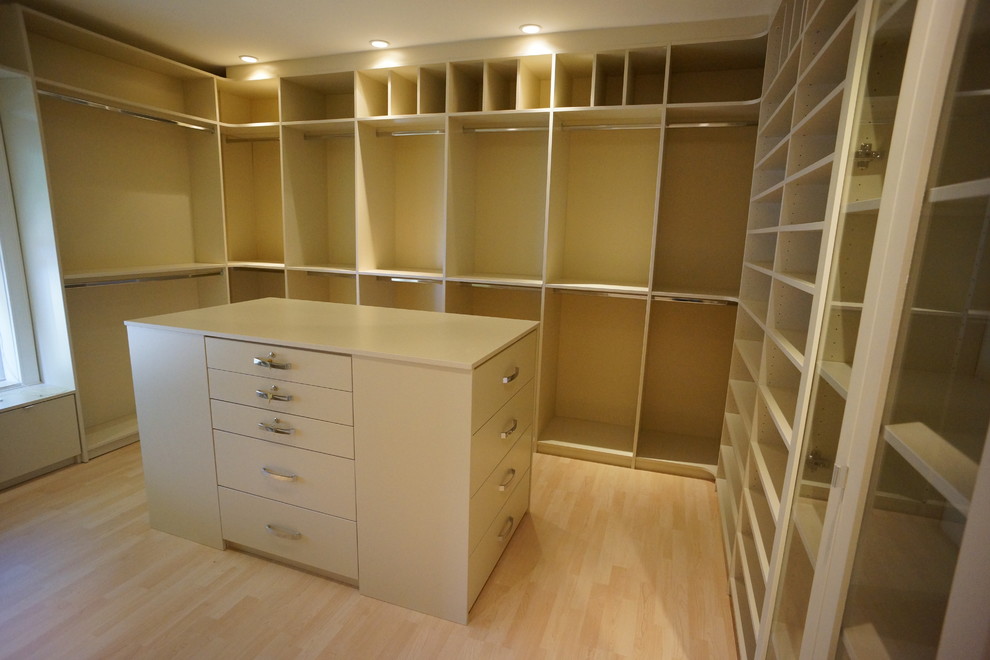 Large elegant gender-neutral light wood floor walk-in closet photo in Miami with flat-panel cabinets and white cabinets